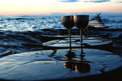 Close-up of beer in sea against sky during sunset