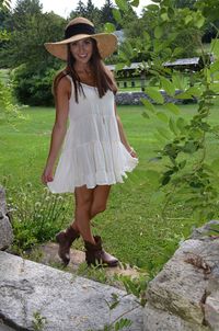 Portrait of beautiful woman wearing white dress standing on grass at park