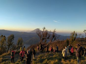 People on mountain road against sky during sunset