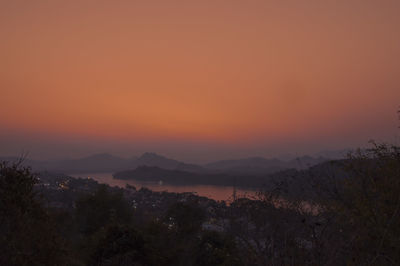Scenic view of silhouette mountains against orange sky