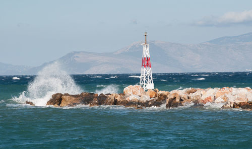 Lighthouse by sea against sky