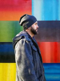 Young man standing against multi colored wall