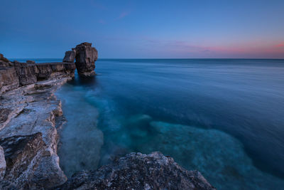 Scenic view of rock formation in sea against sky