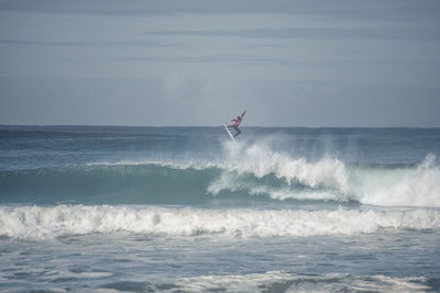 Surfer in sea against sky