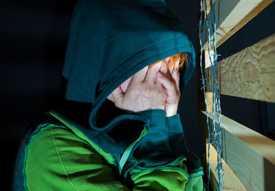 Close-up of woman covering face by wood