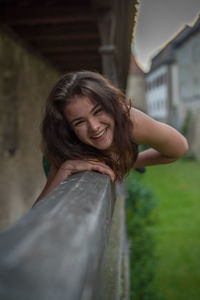 Portrait of cheerful young woman leaning on railing