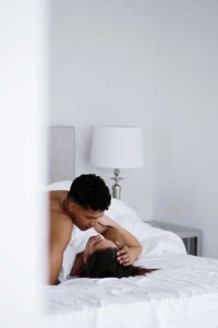 Young woman using mobile phone while lying on bed at home