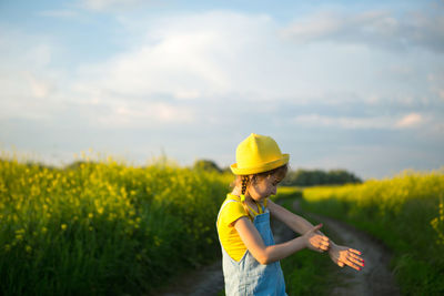 Rear view of woman standing on field against sky