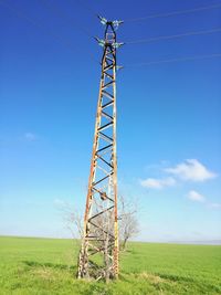 Low angle view of electricity pylon on field against clear sky