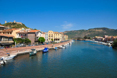 Buildings by sea against blue sky