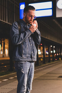 Young man igniting cigarette while standing at night