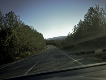 Road amidst trees seen through car windshield