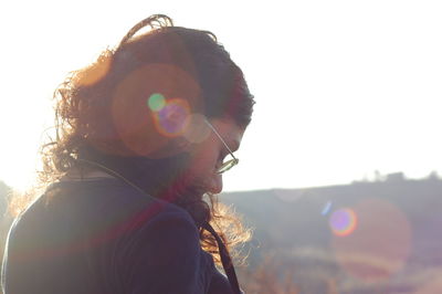 Side view of woman standing against sky