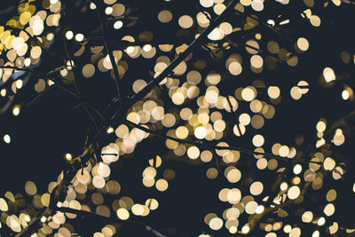 Low angle view of illuminated lighting equipment against black background