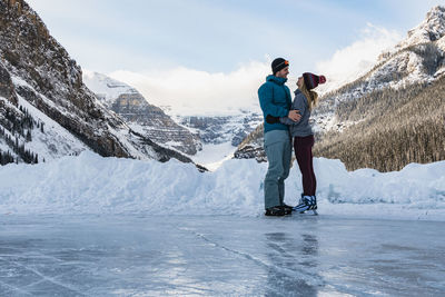 Young couple skating together on frozen lake louise in winter