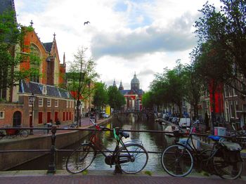 Bicycle parked by canal against buildings in city