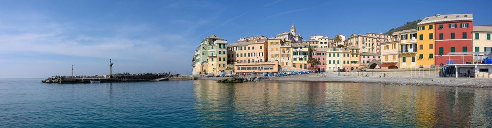 Buildings by sea against blue sky