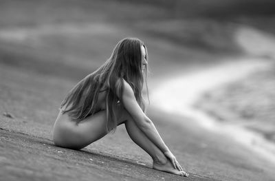 Naked woman sitting at beach