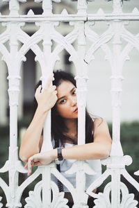 Young woman standing behind white metal fence