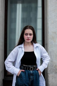 Portrait of young woman standing against wall