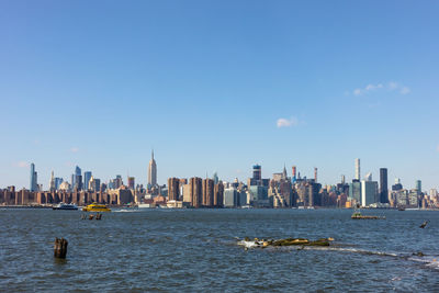 Sea by buildings in city against sky