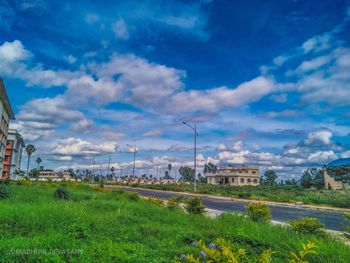 Scenic view of field by buildings against sky