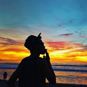 Silhouette people standing on beach against sky during sunset