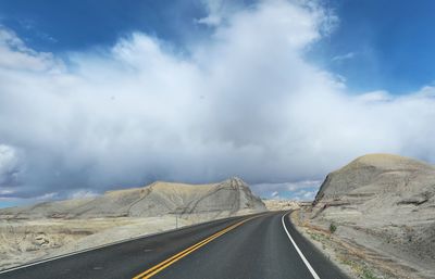 Landscape of grey sand mounds on either side of road in utah