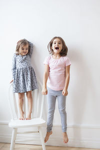 Portrait of a smiling girl standing against wall