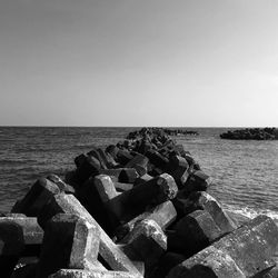 Rocks by sea against clear sky