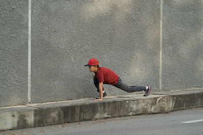 Full length of boy exercising on footpath