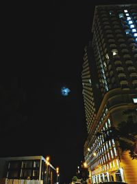 Low angle view of illuminated buildings against sky at night