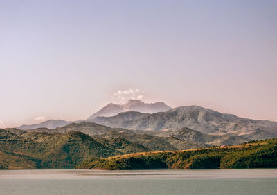 Scenic view of lake by mountains against sky