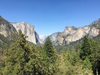 Low angle view of rocky mountains against clear blue sky