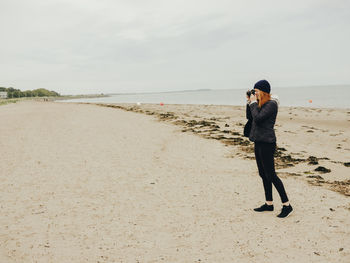 Woman taking photos on beach in scotland