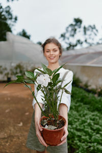 Portrait of young woman holding potted plant