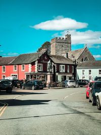 Cars on road by buildings against sky