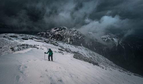 Woman hiking on snowcapped mountain during storm cloud