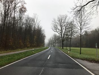 Empty road amidst trees against sky