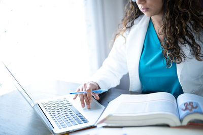 Midsection of woman using mobile phone while sitting on table