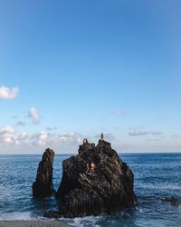 Rock formation in sea against blue sky