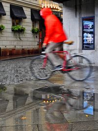 Blurred motion of man riding bicycle on road in city