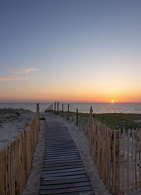 Wooden pier on sea against sky during sunset