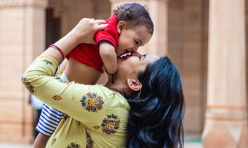 Cute toddler baby boy smiling at mother hand and touch in casual appearance at outdoor