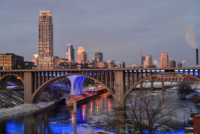 Bridge over river in city against sky