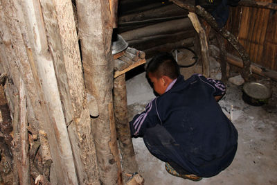 Rear view of man sitting on wood