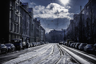 Railroad track amidst parked vehicles in city during winter