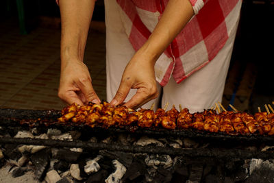 Midsection of man preparing food on barbecue grill