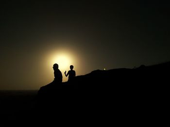 Silhouette friends standing against clear sky during sunset