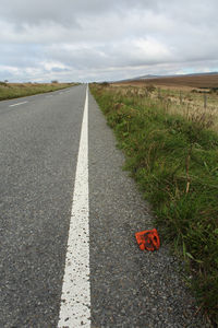 Road amidst grass against sky